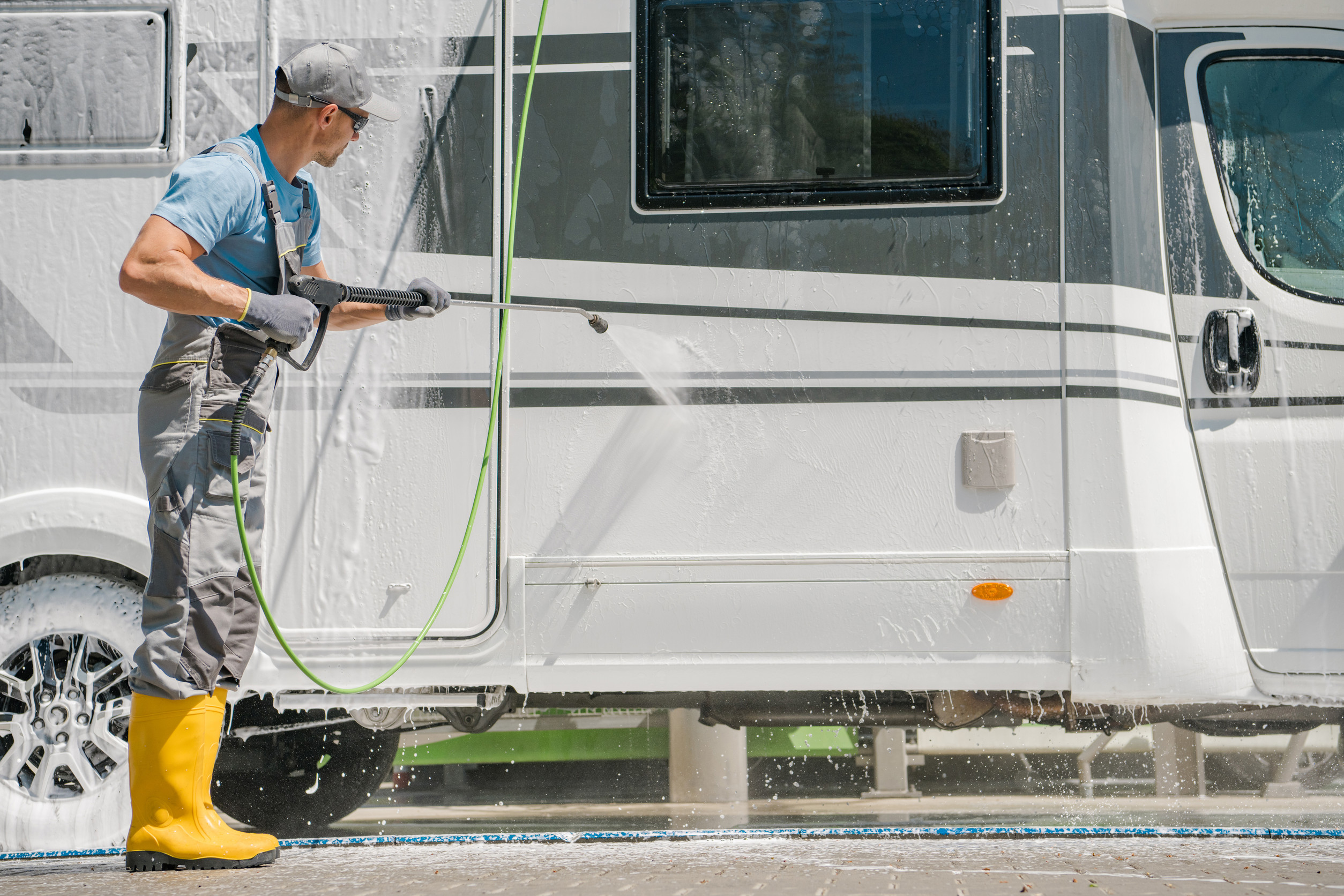  A man is pressure washing his RV.